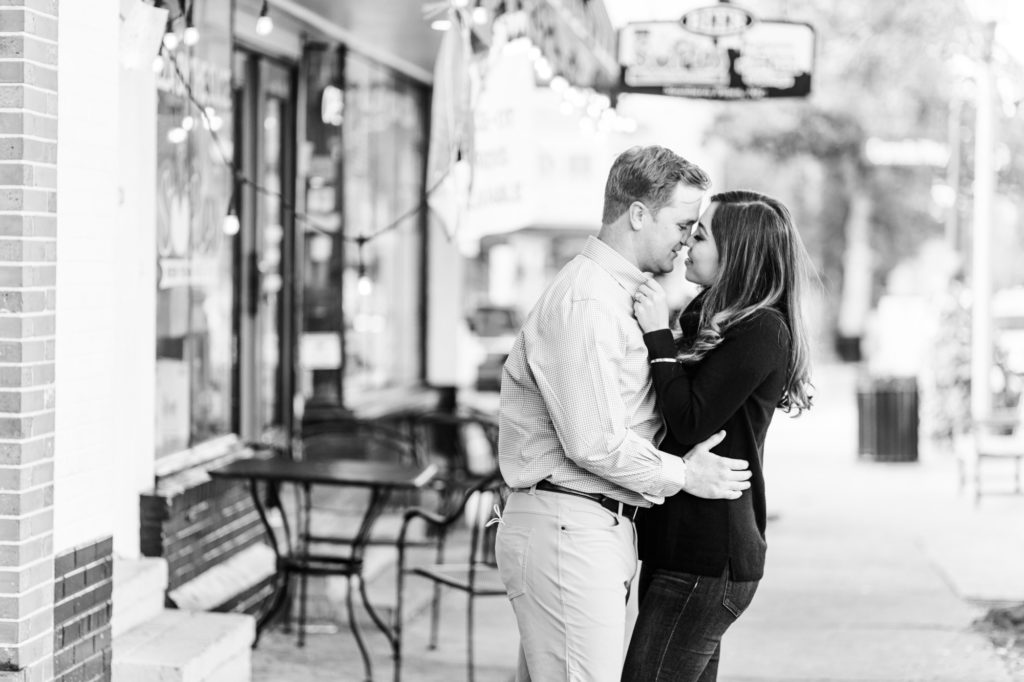 A couple kissing in front of a quaint pizza shop in a charming downtown in North Carolina