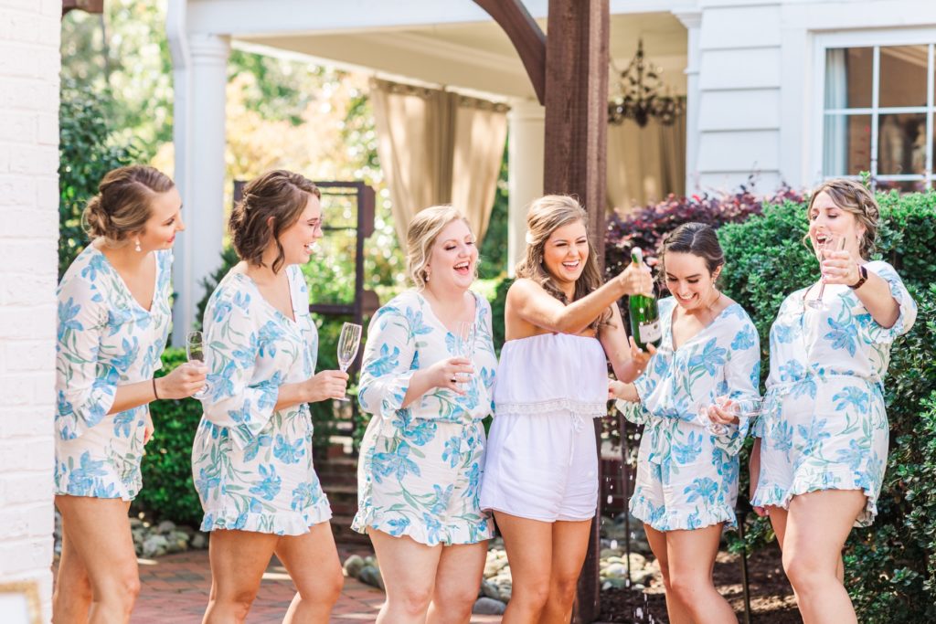 Bridesmaid popping a bottle of champagne at the Highgrove Estate in Fuquay-Varina| Photo by Tierney Riggs Photography