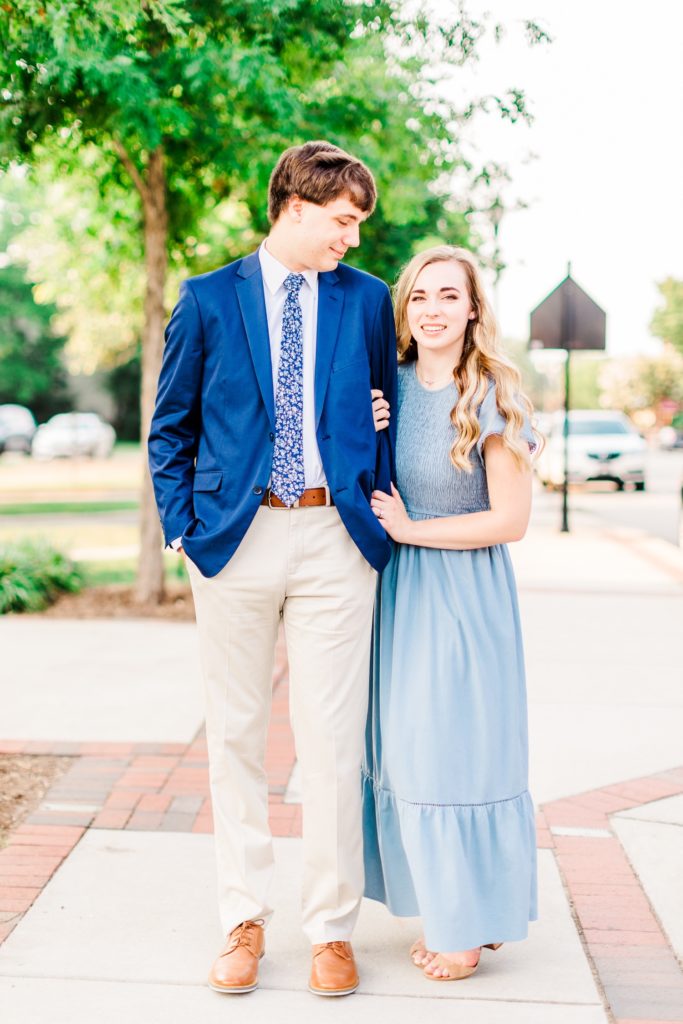 A couple smiling for their engagement session in downtown Cary