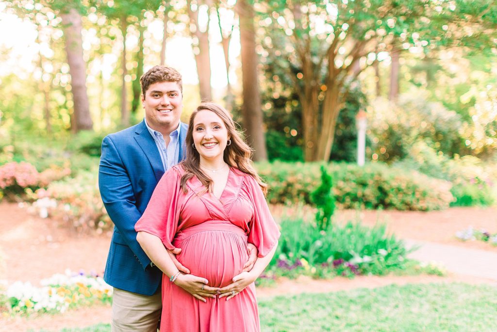 A couple smiling in a garden by Raleigh maternity photographer Tierney Riggs