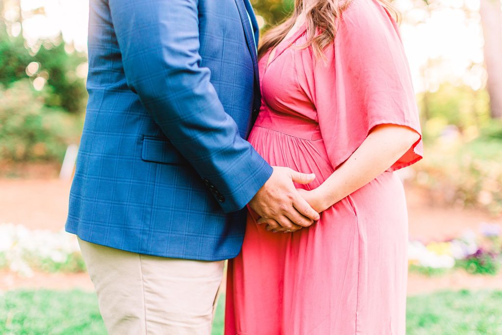 A couple holding hands in a garden by Raleigh maternity photographer Tierney Riggs