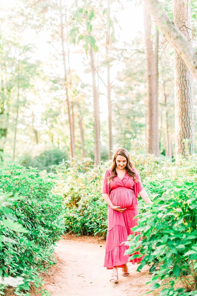 A mom to be walking in a garden captured by Raleigh maternity photographer Tierney Riggs