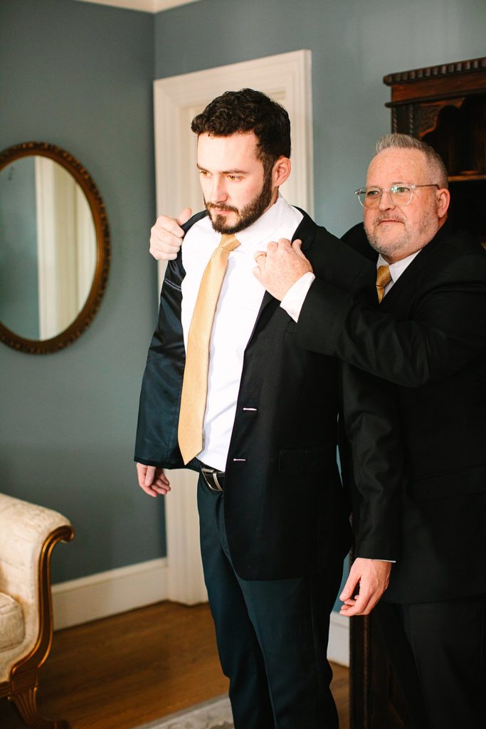 Groom's dad helping him into his jacket before his Highgrove Estate Wedding