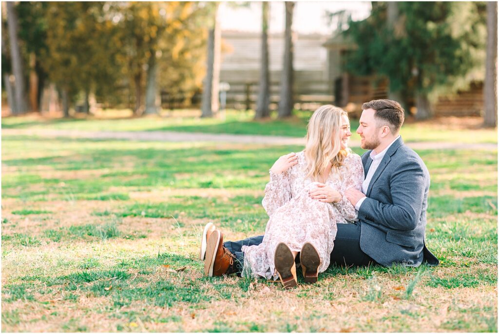 Couple sitting and talking in a field of green grass for their spring engagement photos