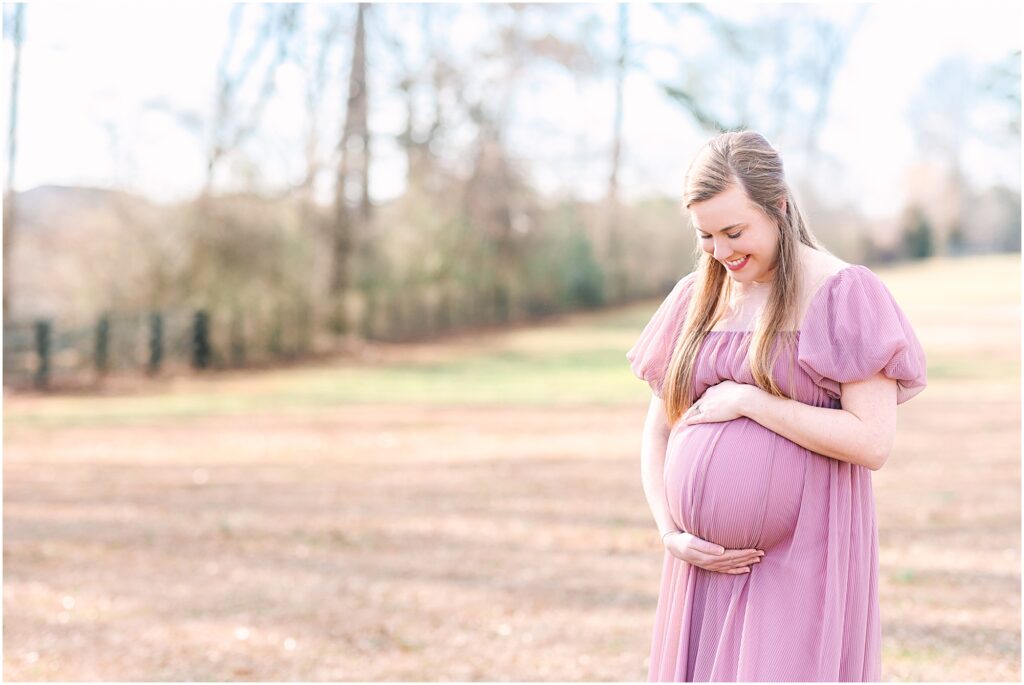 An expecting mother posing in a field for her maternity session in Holly Springs, NC