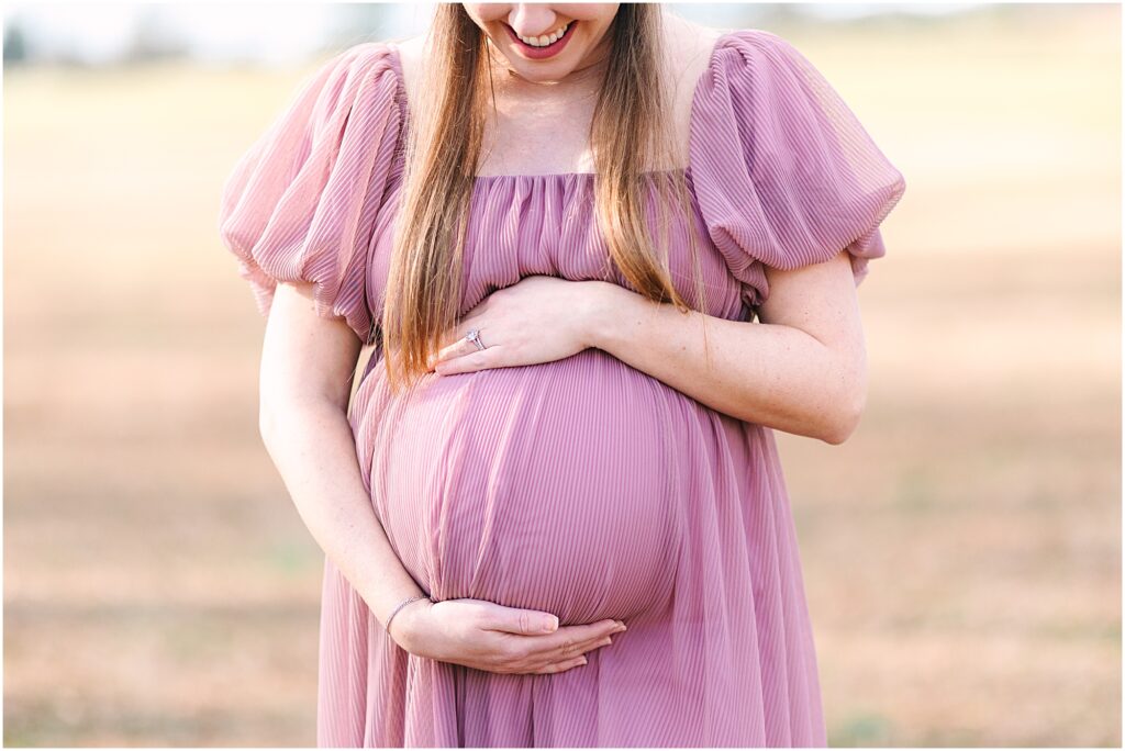 An expecting mother posing in a field for her maternity photos.