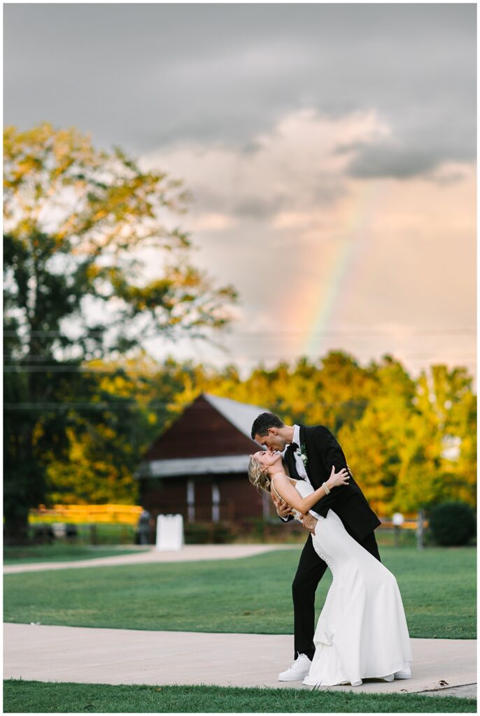 A couple kissing underneath a rainbow on their wedding day