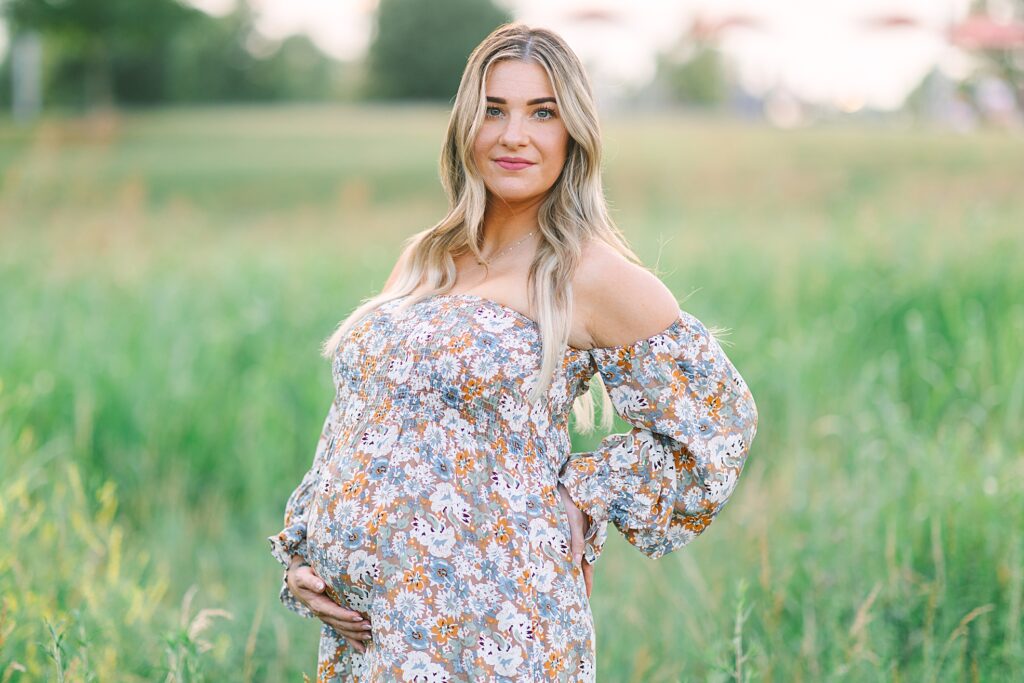 A photo of a mom in a field taken by Raleigh Maternity Photographer, Tierney Riggs