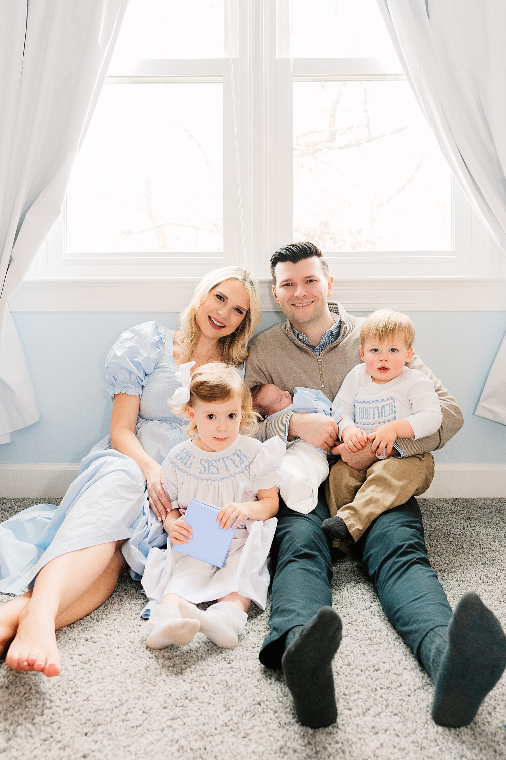 A family sitting in a nursery having newborn photos made in Apex, NC